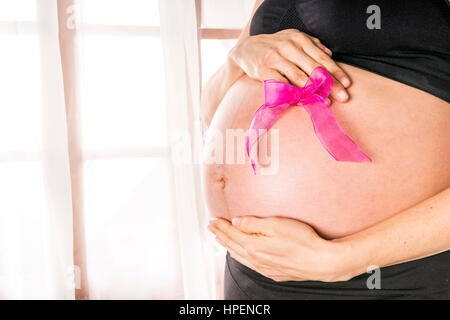 Mom holds pink ribbon on her belly Stock Photo