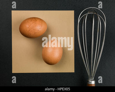 Two Brown Eggs and a Metal Kitchen Utensil Whisk Stock Photo