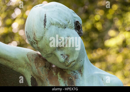 Bronze sculpture of a young man on Cemetery in backlight, Stock Photo