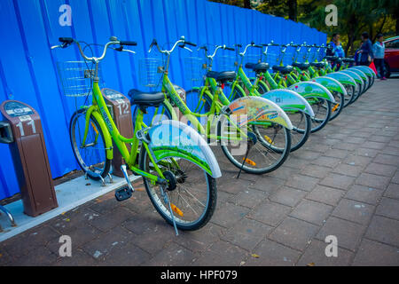 SHENZEN, CHINA - 29 JANUARY, 2017: City bike parking, row of green bikes connected to automatic machines on city street. Stock Photo