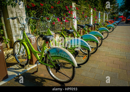 SHENZEN, CHINA - 29 JANUARY, 2017: City bike parking, row of green bikes connected to automatic machines on city street. Stock Photo