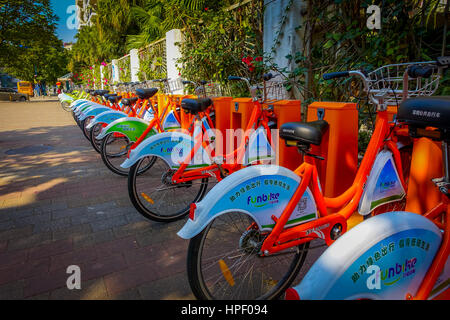 SHENZEN, CHINA - 29 JANUARY, 2017: City bike parking, row of orange bikes connected to automatic machines on city street. Stock Photo