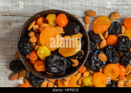 prunes, dried apricots, dried mandarins and almonds in a bowl on a light wooden background. Stock Photo