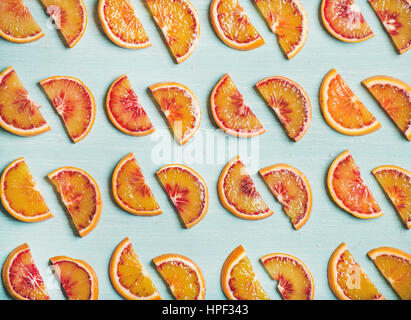 Natural fruit pattern concept. Fresh juicy blood orange slices over light blue painted table background, top view Stock Photo