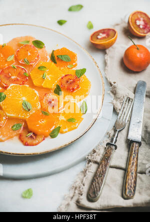 Fresh mixed citrus fruit salad with mint and honey on white ceramic plate over grey background, selective focus. Vegan, vegetarian, healthy, dieting, Stock Photo