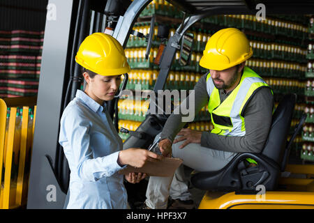 Attentive factory workers checking record on clipboard in factory