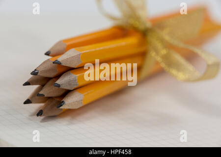 Bunch of pencils wrapped with ribbons on book Stock Photo