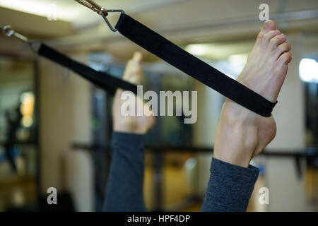Woman performing stretching exercise on reformer in gym Stock Photo