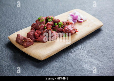 Diced beef and onions on wooden board against black background Stock Photo