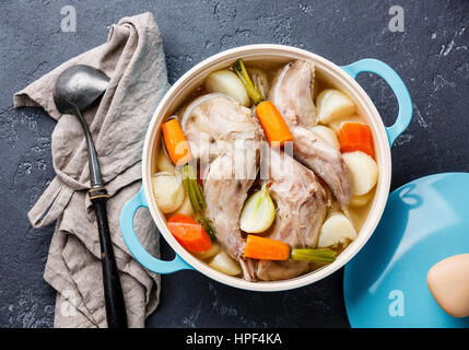 Stewed rabbit with potatoes and carrot in cast iron pan on dark stone background Stock Photo