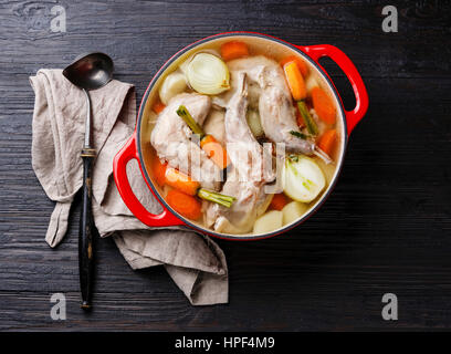 Stewed rabbit with potatoes and carrot in cast iron pan on black burned wooden background Stock Photo