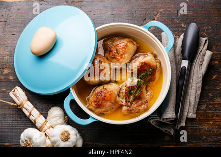 Roast chicken stew in cast iron pan on wooden background Stock Photo