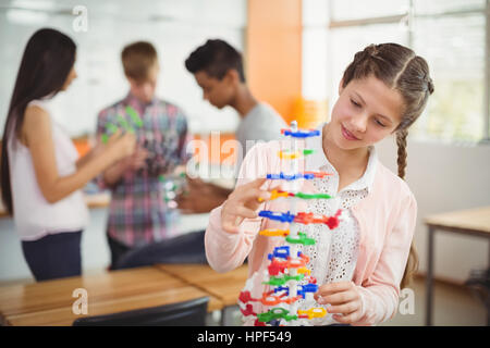 Smiling schoolgirl examining the molecule model in laboratory at school
