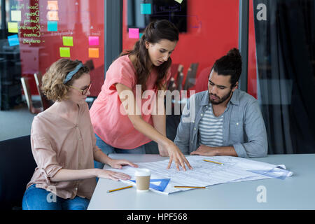 Business executives discussing over blueprint in office Stock Photo