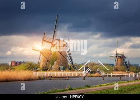 Windmills against cloudy sky at sunset in famous Kinderdijk, Netherlands. Rustic landscape with traditional dutch windmills, bridge, water and sky Stock Photo