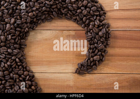 Coffee beans forming shape on wooden table Stock Photo