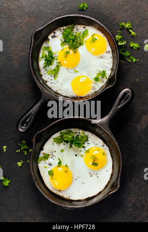 Pans with fried eggs and herbs on old metal background, top view. Food. Breakfast. Healthy food. Stock Photo
