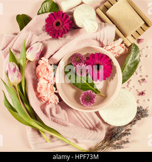 Spa background with sea salt, bowl, flowers, water, soap bar, candles, essential oils, massage brush and flowers,top view. Flat lay. Pink background Stock Photo