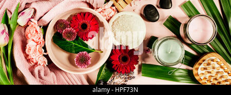 Spa background with sea salt, bowl ,flowers, water, soap bar, candles, essential oils, massage brush and flowers,top view. Flat lay. Pink background Stock Photo