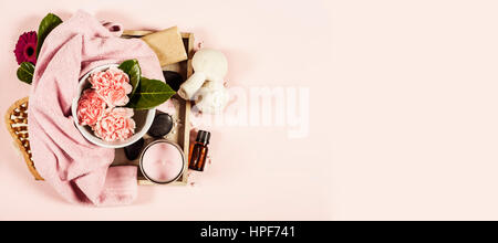 Spa background with sea salt, bowl ,flowers, water, soap bar, candles, essential oils, massage brush and flowers,top view. Flat lay. Pink background Stock Photo