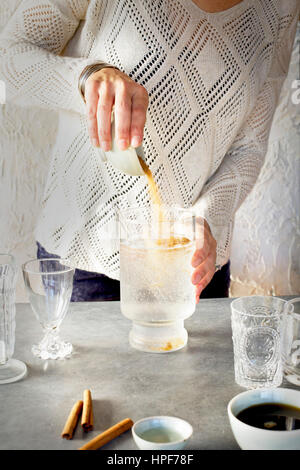 A Women is pouring sugar into Soda Water in glassware. Photographed on dark gray background. Stock Photo