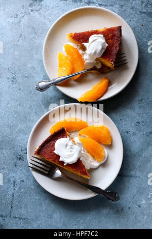 Orange polenta cake slices on a plate served with creme fraiche and fresh orange Stock Photo