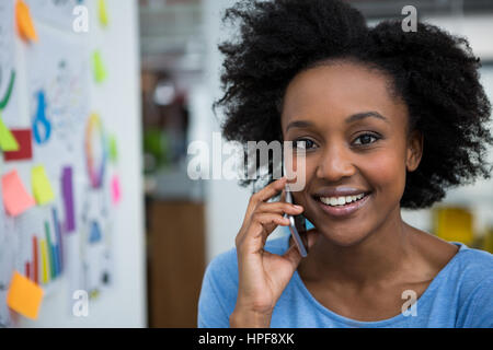 Smiling graphic designer talking on mobile phone in creative office Stock Photo