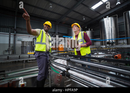 Two factory workers looking up in drinks production plant Stock Photo