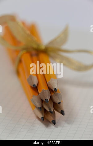 Bunch of pencils wrapped with ribbons on book Stock Photo