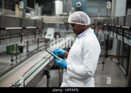 Factory engineer using digital tablet in the factory	Factory engineer using digital tablet in drinks production plant Stock Photo