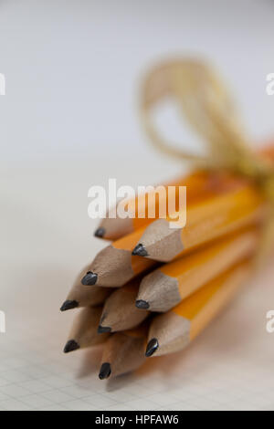 Bunch of pencils wrapped with ribbons on book Stock Photo