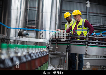 Two factory workers monitoring cold drink bottles at drinks production plant Stock Photo