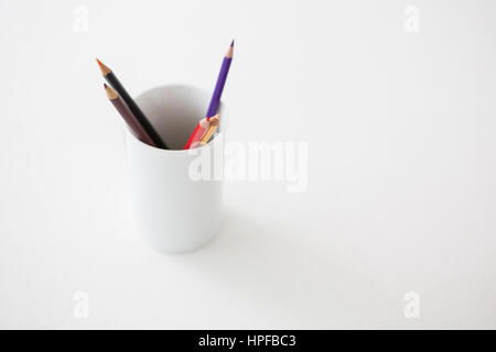 Colored pencils kept in pencils holder on white background Stock Photo