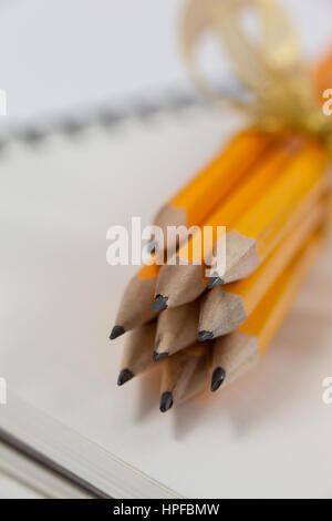 Bunch of pencils wrapped with ribbons on book Stock Photo