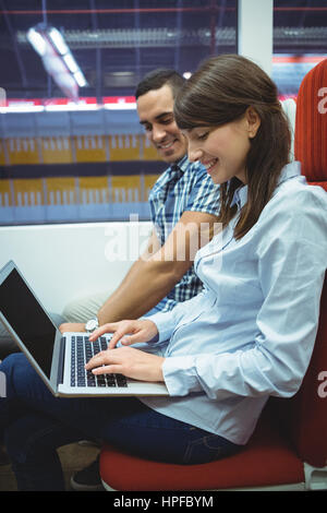 Smiling executives using laptop travelling in train Stock Photo