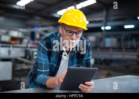 Attentive factory worker using a digital tablet in factory Stock Photo
