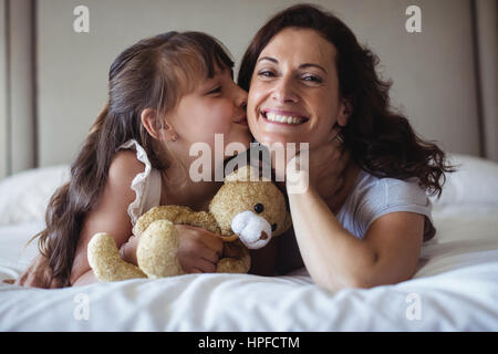 Woman kissing teddy bear in living room stock photo