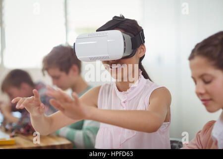 School girl sitting in classroom using virtual reality headset at school Stock Photo