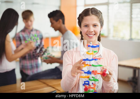 Portrait of smiling schoolgirl examining the molecule model in laboratory