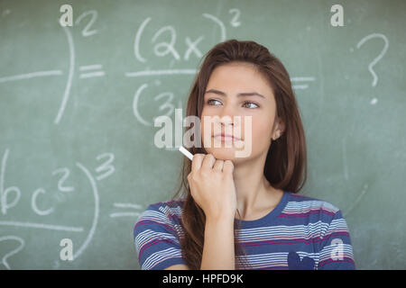 Thoughtful schoolgirl pretending to be a teacher in classroom at school Stock Photo