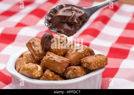 A close up image of a bowl of small pretzels with chocolate frosting on a spoon. Stock Photo
