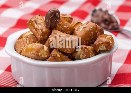 A close up image of a bowl of small pretzels with chocolate frosting on a spoon. Stock Photo