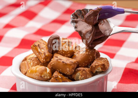 A close up image of a bowl of small pretzels with chocolate frosting on a spoon. Stock Photo