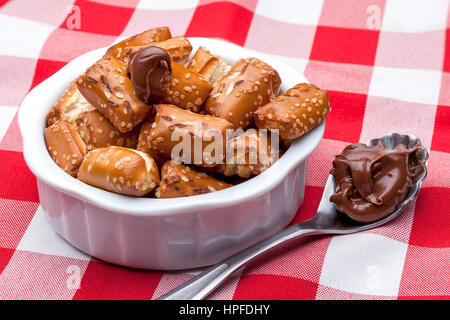 A close up image of a bowl of small pretzels with chocolate frosting on a spoon. Stock Photo