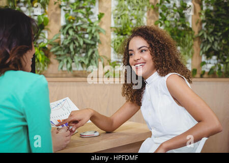 Two female business executives interacting with each other at desk in office Stock Photo