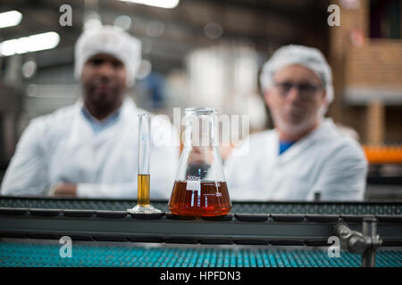 Row Line Enginering In a beverage factory line two engineers inspect product bottles on the ...