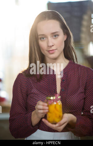 Portrait of a shop assistant holding a jar of pickle in grocery shop Stock Photo