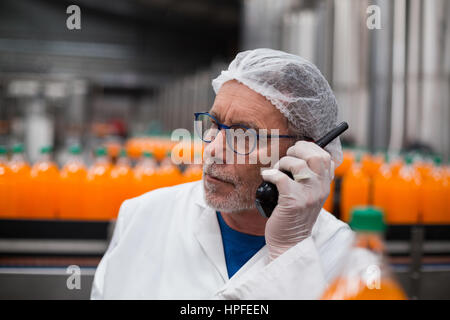 Factory engineer talking on walkie talkie in bottle factory Stock Photo