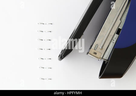 Blue stapler and staples with paper on white table Stock Photo