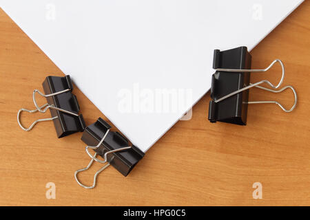 three clips stapling papers on the table Stock Photo